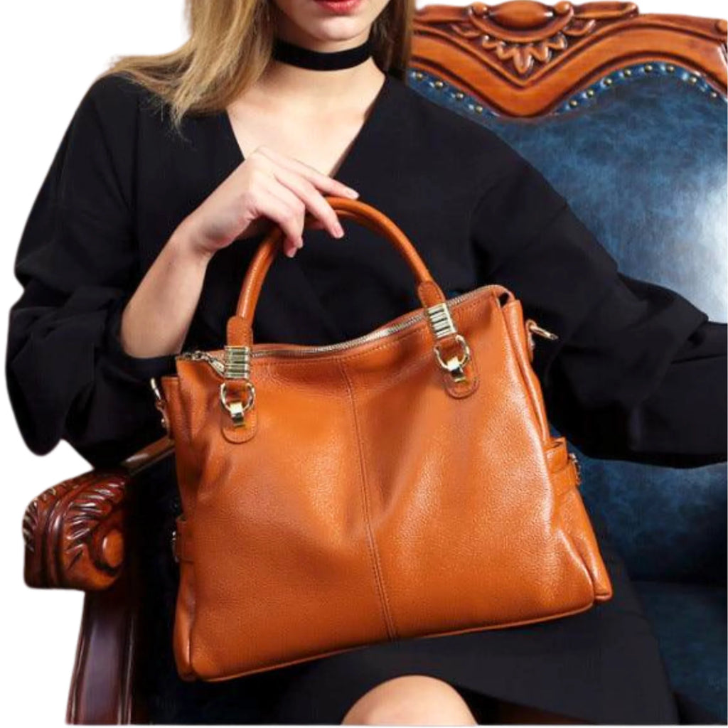 Rindsleder-Handtasche in Cognac mit Kurzgriff und goldener Schnalle, getragen im Sitzen