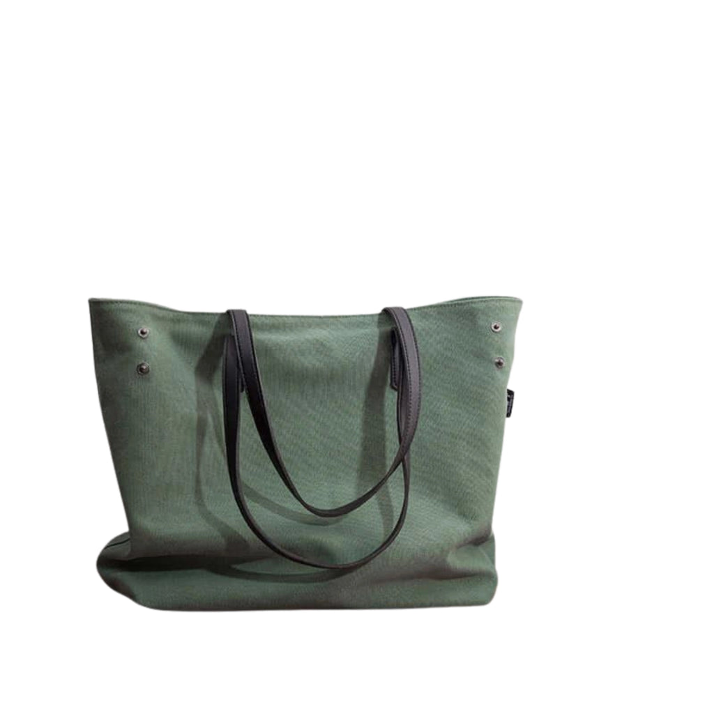 Grün gefärbte Canvas-Tasche mit schwarzen Henkeln und Metallnieten – klar, strukturiert und unauffällig