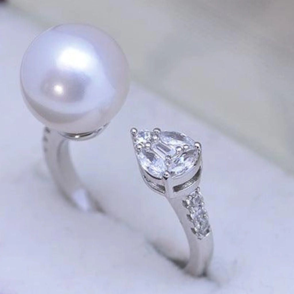 Close-up auf die Edelsteinfassungen: Perle und Tropfen-Zirkonia auf offenem Ring aus Silber.