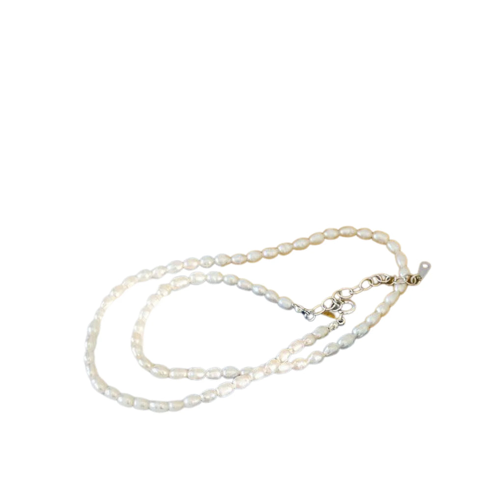 Zarte Perlenkette mit ovalen Süsswasserperlen in Reisform, flach fotografiert mit 925 Silberverschluss