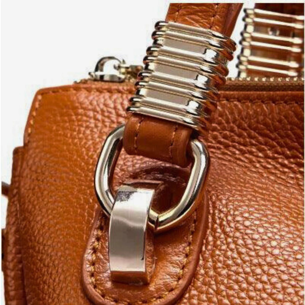 Nahaufnahme der goldenen Metallringe am Tragegriff einer Echtleder-Handtasche in Cognac