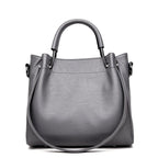 Graue Damenhandtasche mit klassischer Bucketform, glatter Oberfläche und Retro-Look