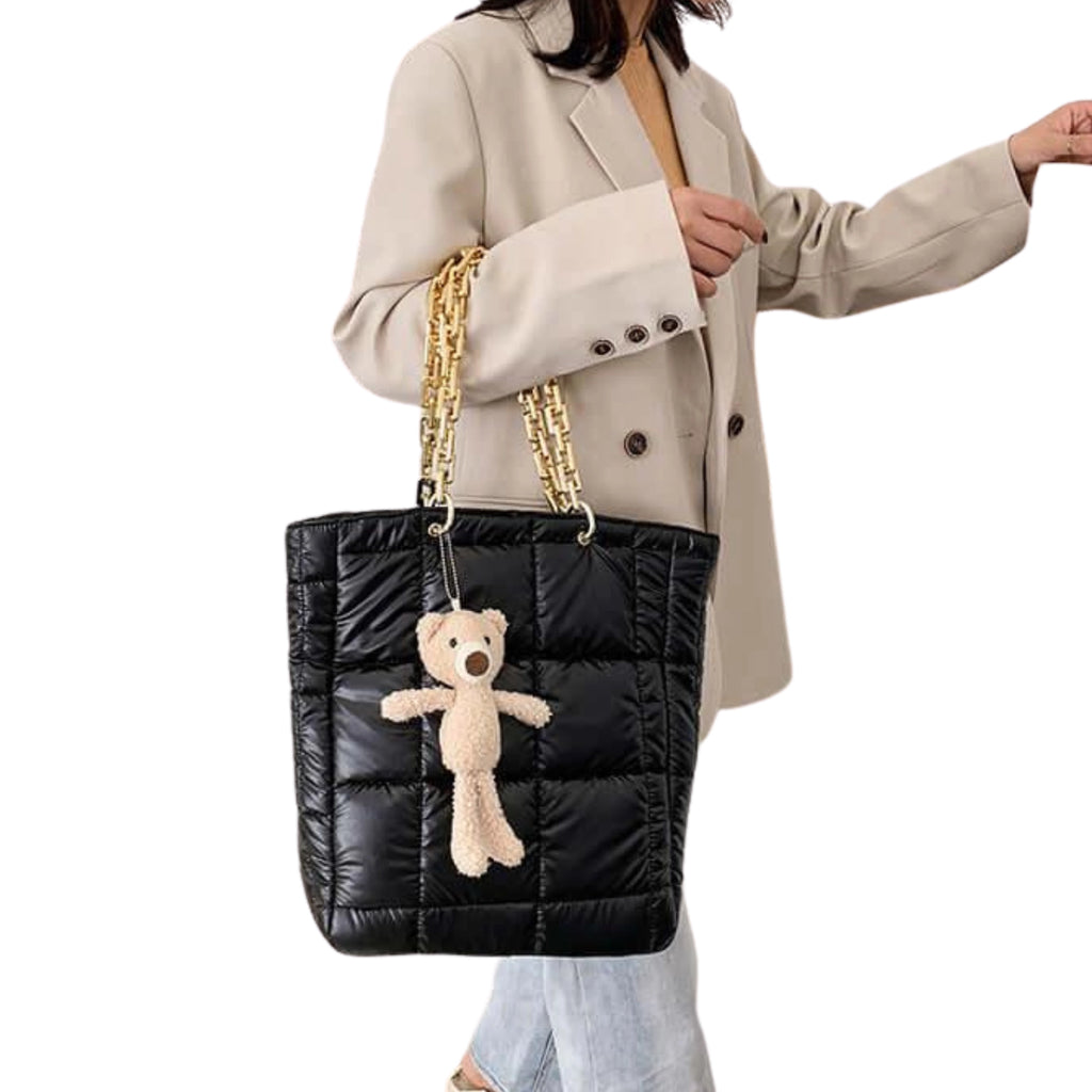 Vertikalformat der schwarzen Pufftasche getragen an Schulter mit schwarzer Kette und Outfit in Beige