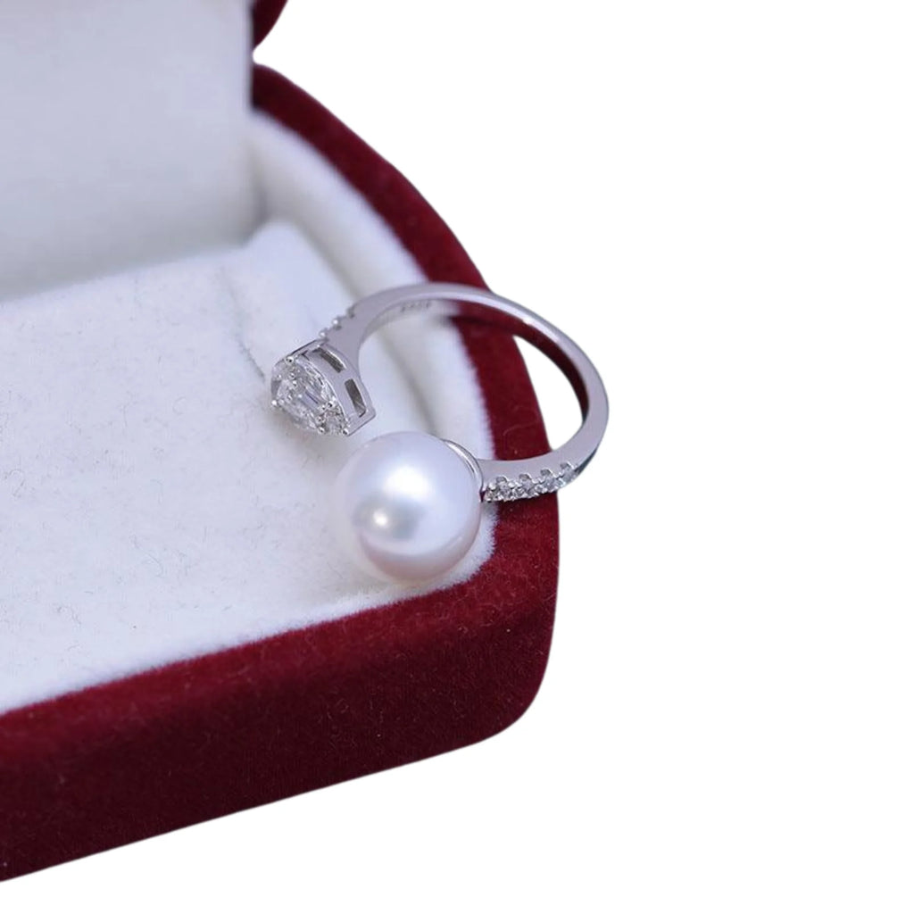 Silberring mit freistehender Perle und Zirkoniakopf, präsentiert auf weissem Samtkissen.