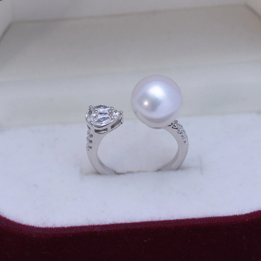 Moderner offener Ring aus 925 Silber mit runder weisser Perle und Tropfen-Zirkonia, fotografiert in Schmuckbox.
