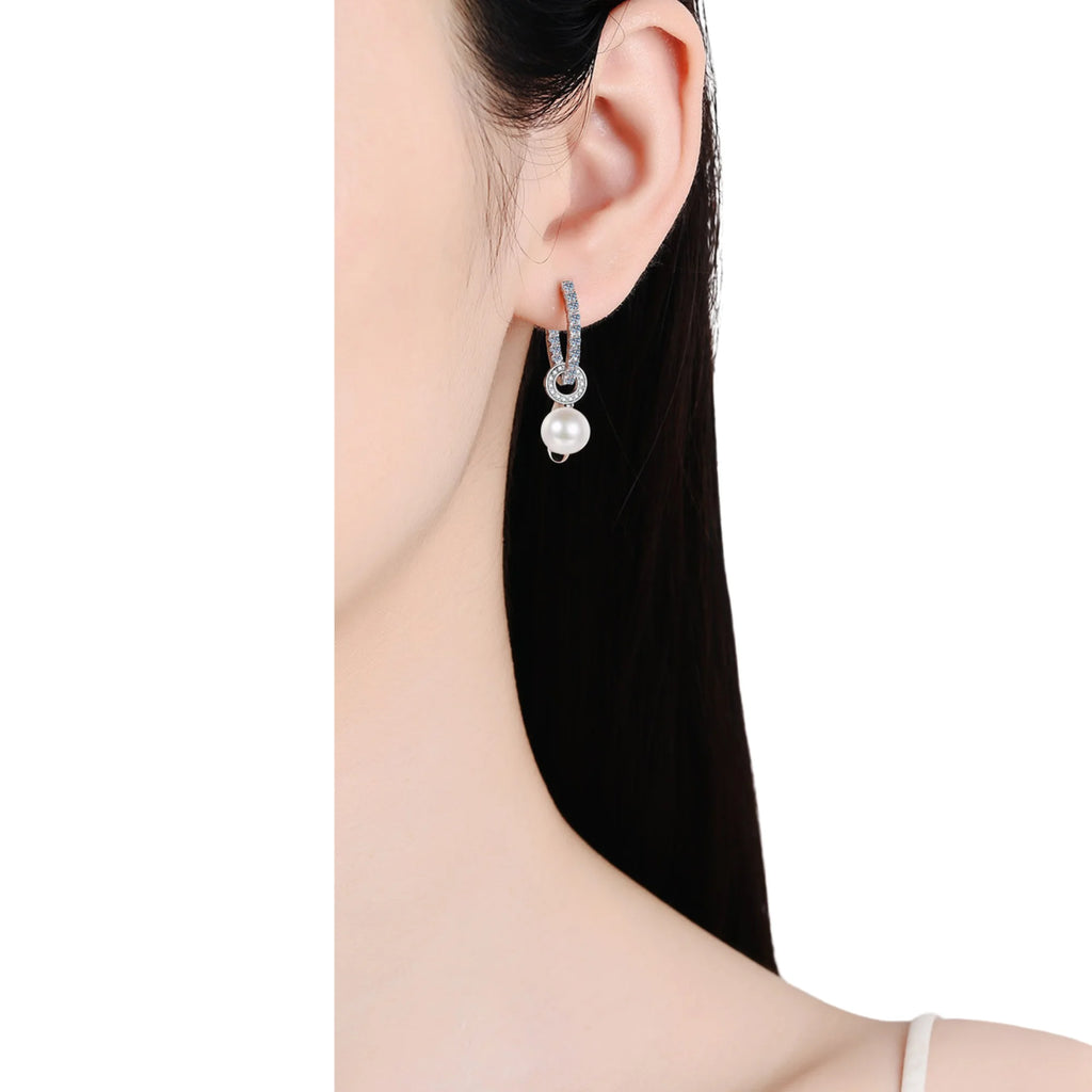 Ohrstecker aus 925 Silber mit Perlenanhänger und kreisförmigem Zirkonia-Design am Ohr einer Frau