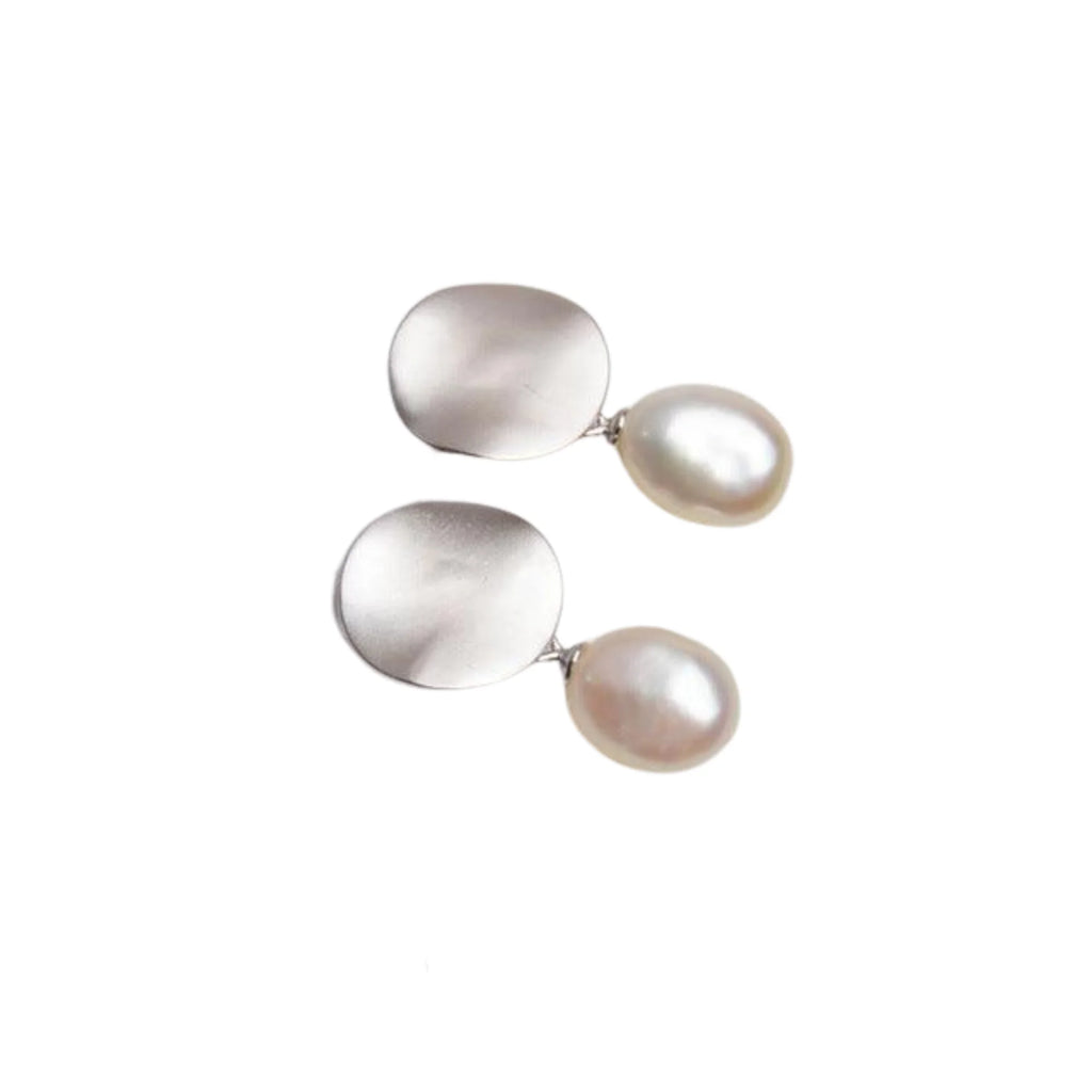 Minimalistische Ohrstecker aus mattem Silber mit organischer Süsswasser-Barockperle – ruhig, flächig, modern.