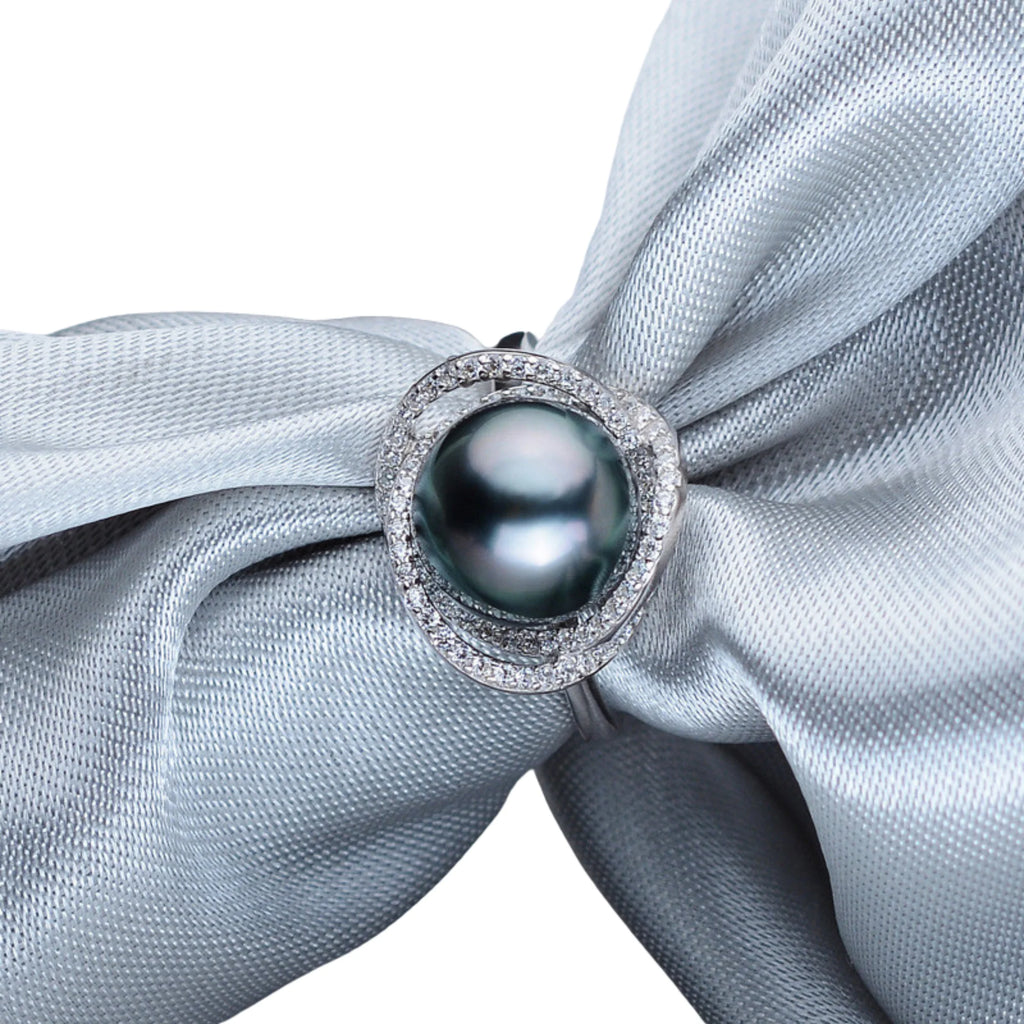 Dunkle Tahitiperle auf silbernem Ring, drapiert auf einem hellen Seidentuch