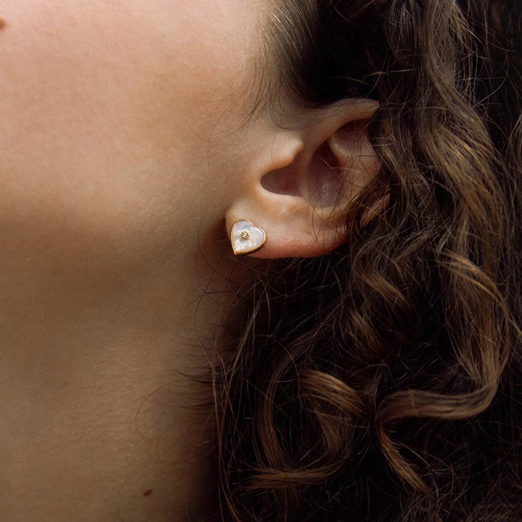 Detailaufnahme eines Ohrsteckers in Herzform – mattes Perlmutt mit zentralem Lichtpunkt