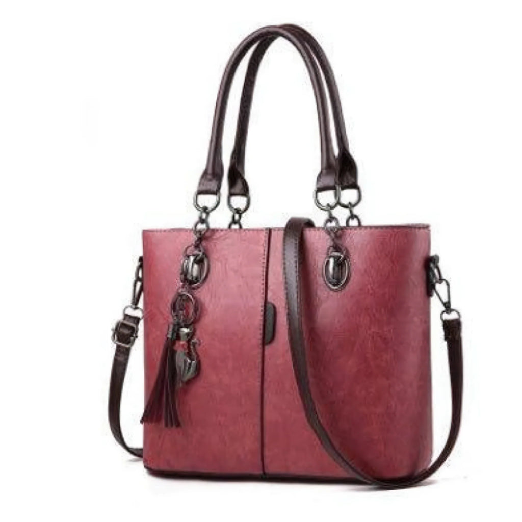 Weinrote Handtasche mit strukturierter Oberfläche, braunen Griffen und Quaste