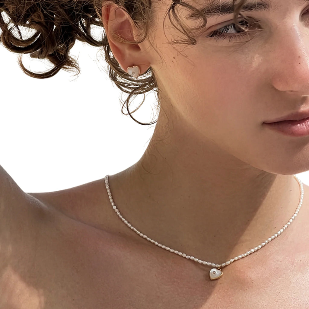 Model trägt zartes Perlmutt-Set: Herz Ohrstecker und passende Halskette – ruhiger Look in Weiss und Gold