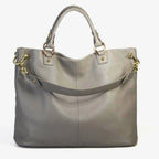 Graue Rindsledertasche mit Lychee-Prägung, goldenen Karabinern und kurzem Griff