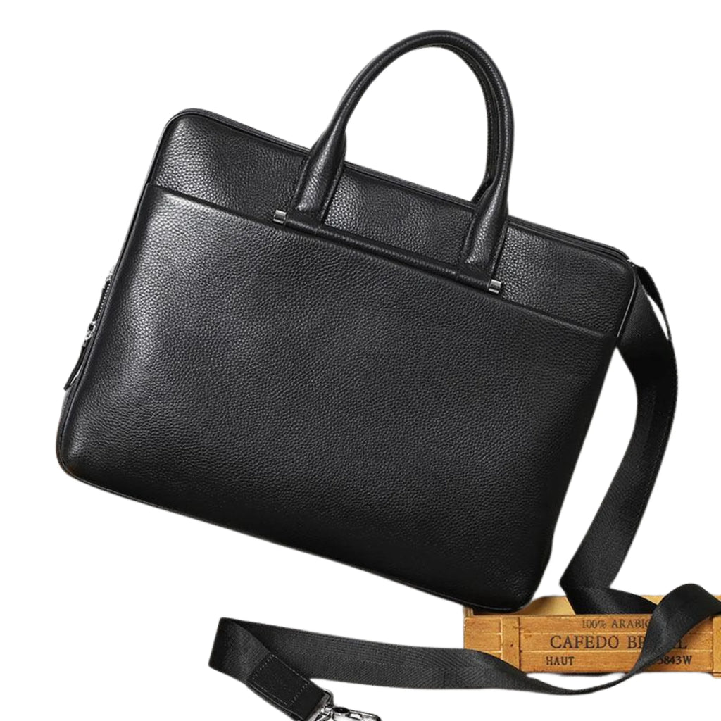 Matte Aktentasche mit Griffen und Gurt diagonal liegend – formstabil, edel, zurückhaltend.