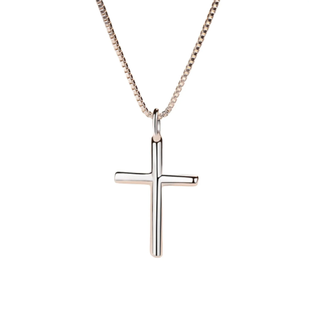 Polierter Kreuzanhänger in Nahaufnahme auf Porzellanteller