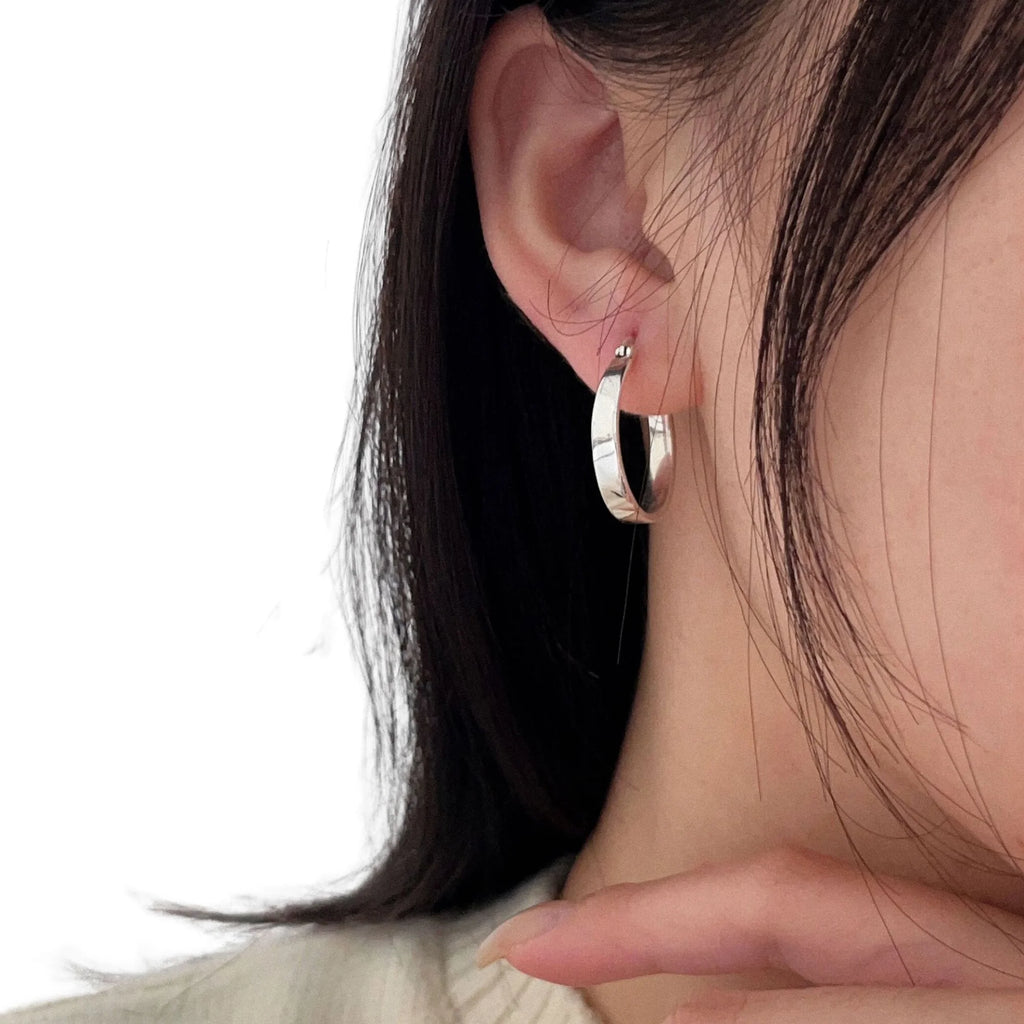 Silbercreole in mittlerer Breite, getragen am Ohr – glatt, ohne Gravur