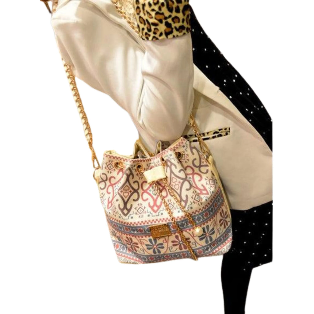 Frau mit Eimertasche im Ethno-Look und goldener Kette über der Schulter – kombiniert mit Blazer