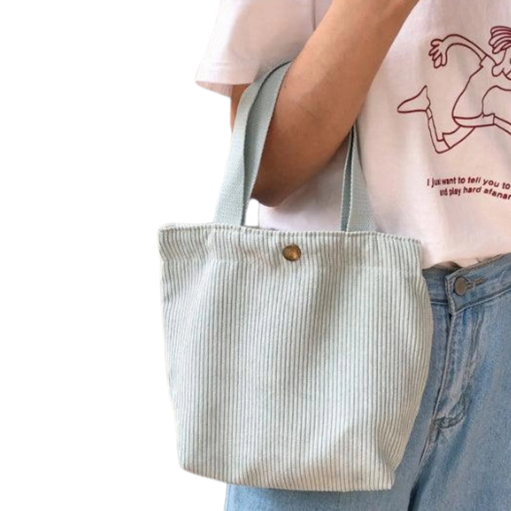 Cordtasche in Mist Green, kompakt über dem Arm getragen, kombiniert mit weissem Shirt