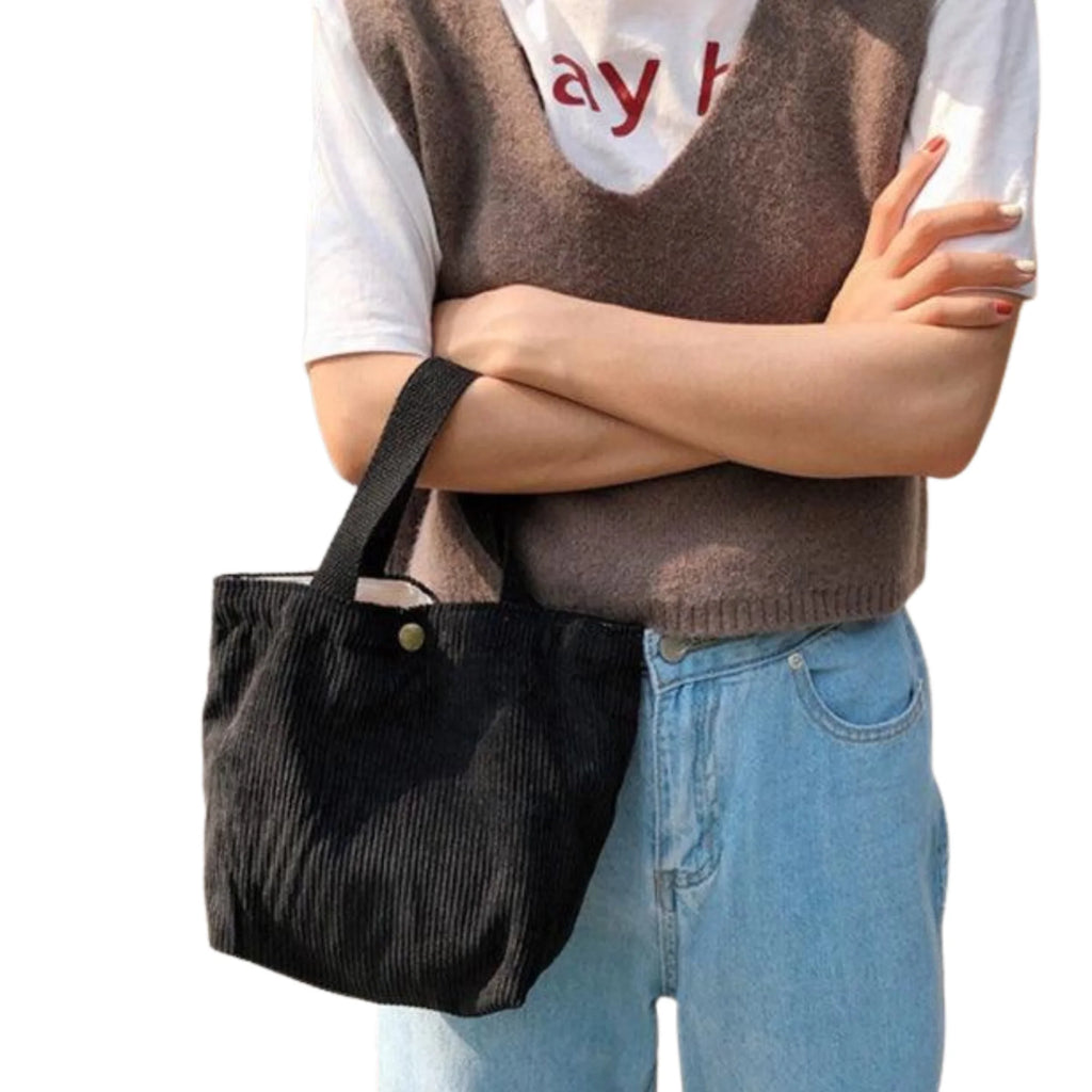 Schwarze Cordtasche Raw Black, lässig in der Armbeuge getragen mit Freizeitlook