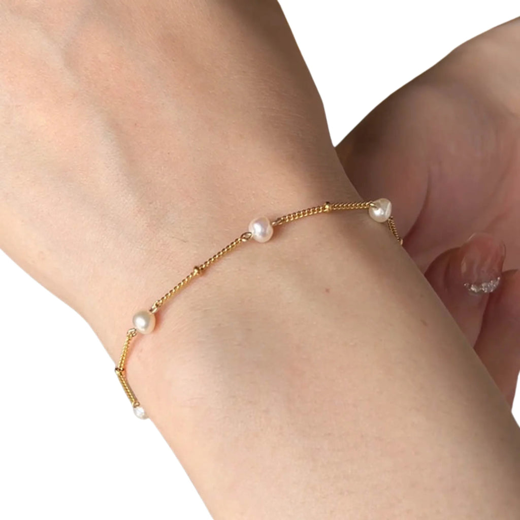 Goldarmband mit fünf Perlen – getragen bei Tageslicht, fast schwerelos am Handgelenk