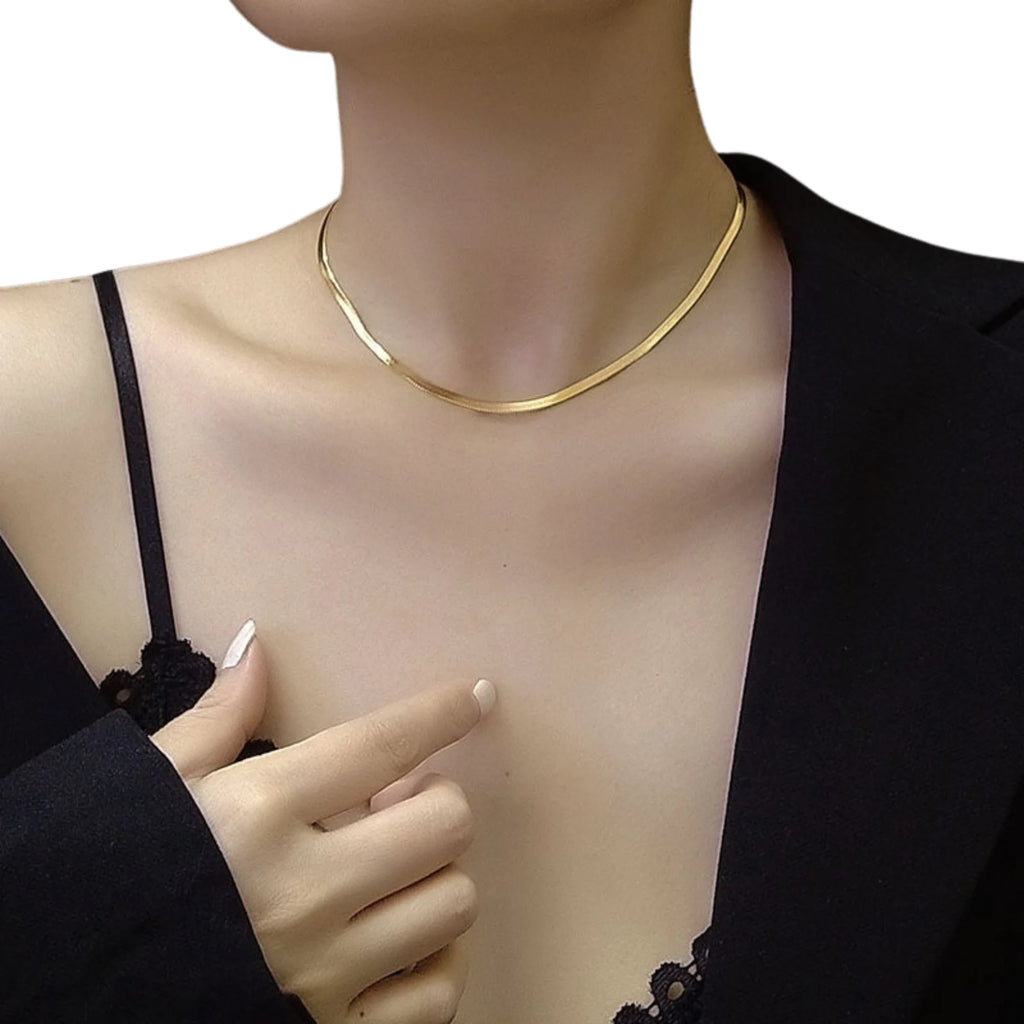 Flache vergoldete Schlangenkette – kombiniert im Layering-Look, leicht und modern