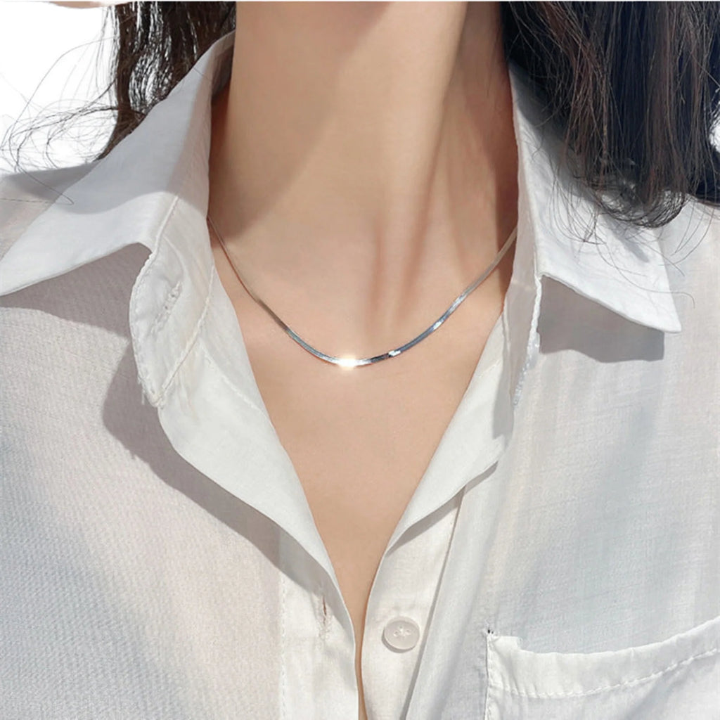 Nahaufnahme der getragenen flachen Schlangenkette in Silber – feine Struktur, reduziertes Design