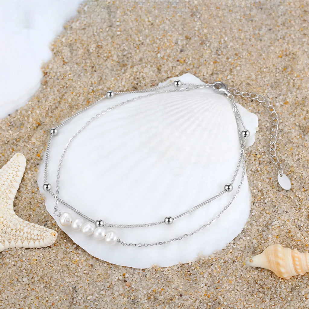 Fusskette in Silberoptik mit Süsswasserperlen – sichtbar ohne Bedeutung, platziert im Sand