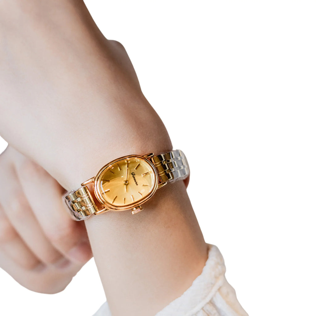 Dezente Uhr mit goldfarbenem Gehäuse und Metallband, getragen am Handgelenk.