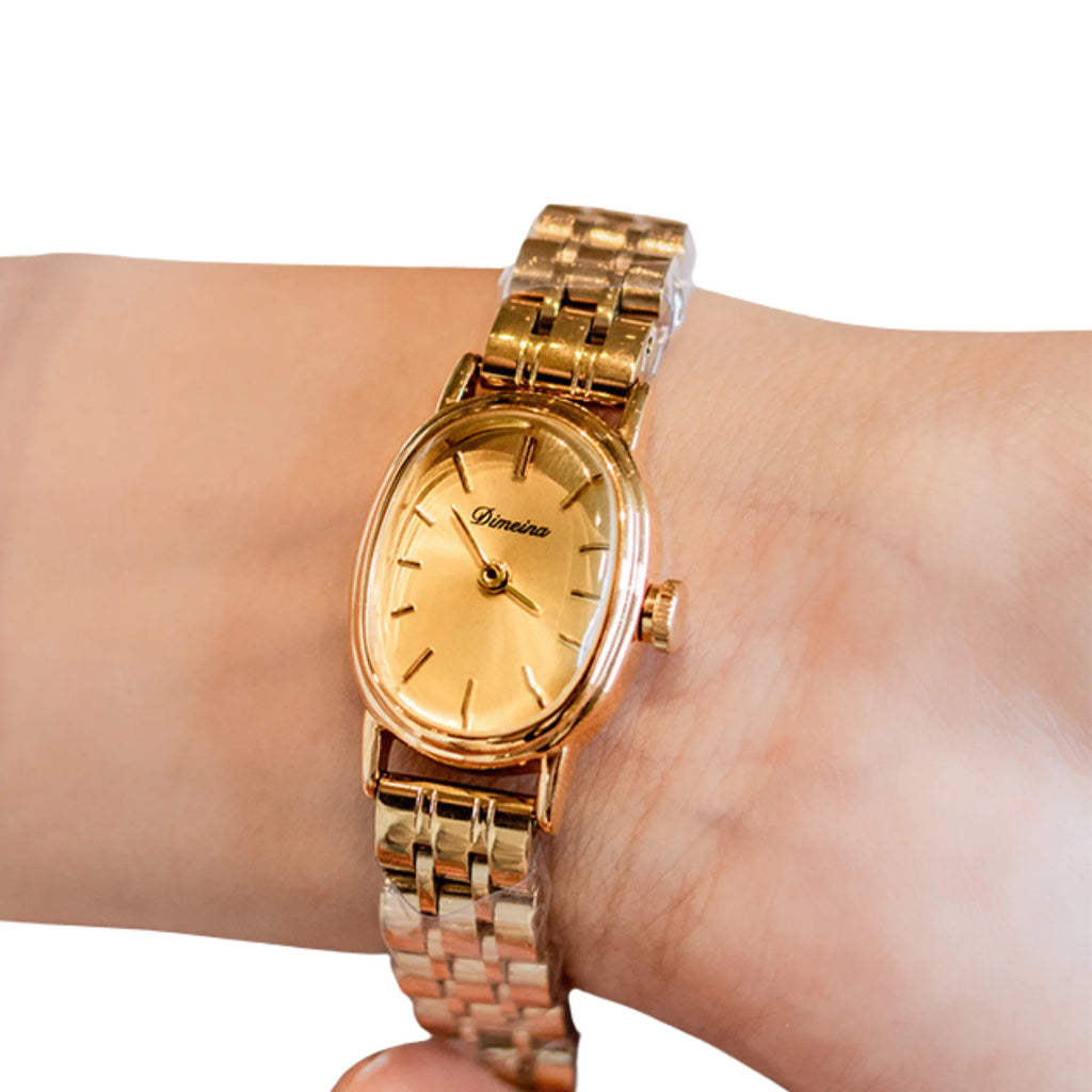 Klassische Armbanduhr mit ovalem Gehäuse und goldfarbenem Band, getragen am Handgelenk.