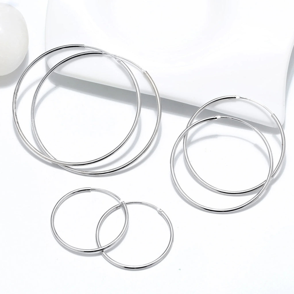 Kreis-Ohrringe in Silber, nebeneinander flach auf weissem Untergrund platziert