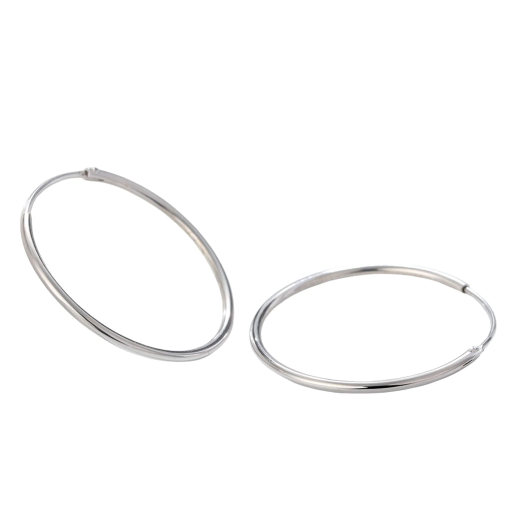 Zwei silberne Ohrringe im Kreisdesign diagonal auf weissem Hintergrund