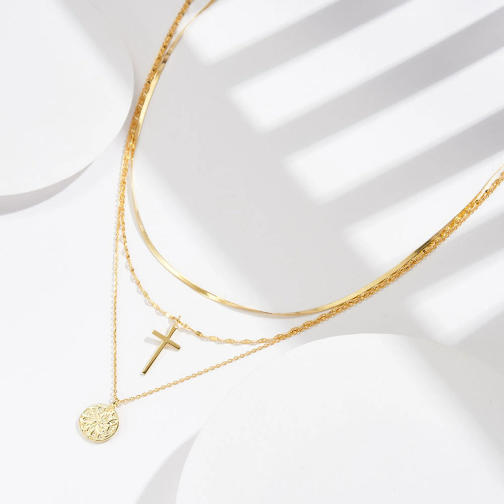 Detailaufnahme der goldenen Kreuzkette auf Haut – ruhiges Symbol mit polierter Oberfläche