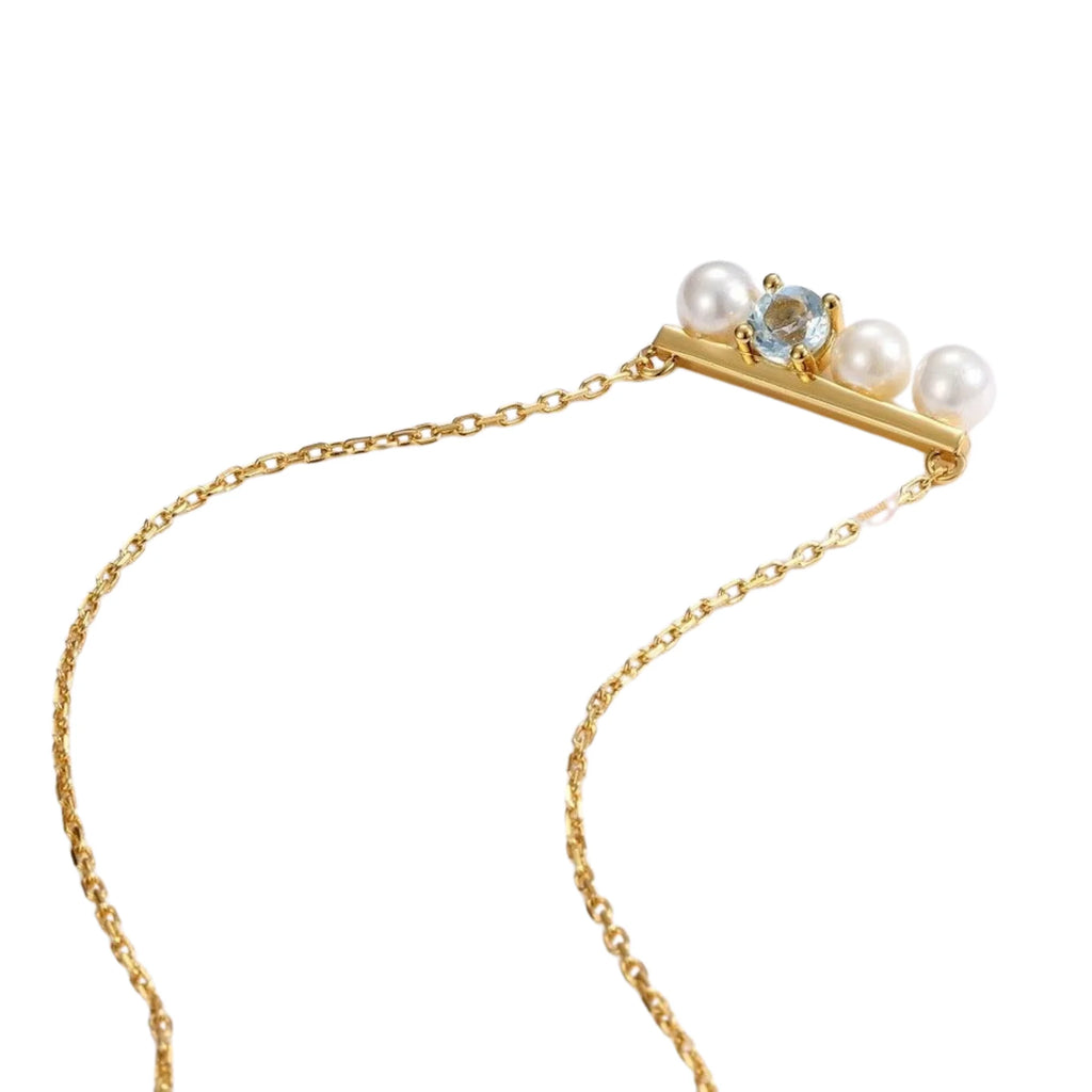 Feine Grafik-Kette mit hellblauem Topas als Zentrum und Perlen auf Goldlinie