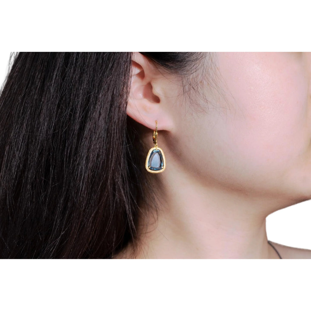 Goldfarbener Ohrhänger mit blauer Fläche am Ohr getragen, ruhig konturiert