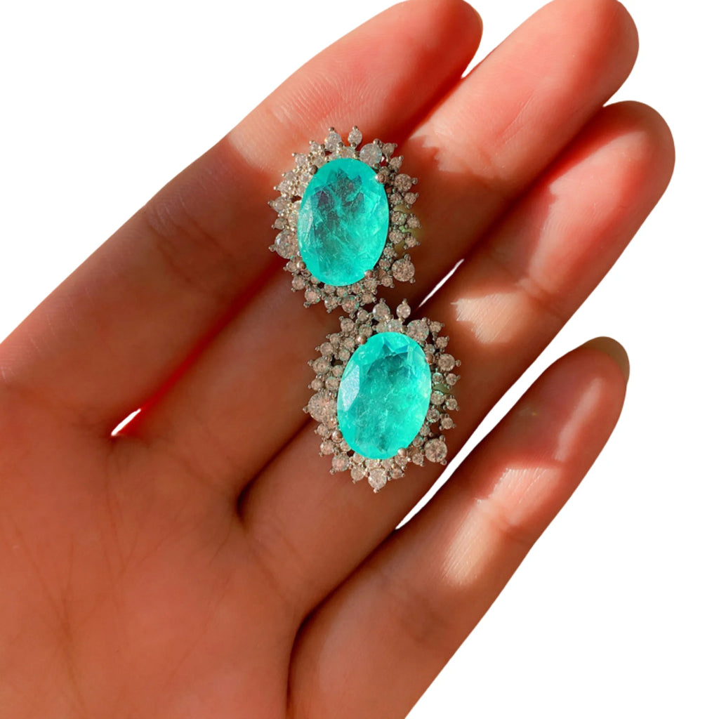 Türkisfarbene Paraiba-Ohrstecker mit Zirkoniafassung – auf Hand fotografiert.