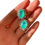 Türkisfarbene Paraiba-Ohrstecker mit Zirkoniafassung – auf Hand fotografiert.