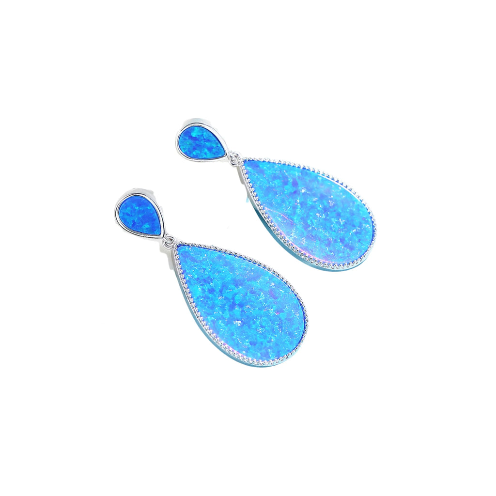 Blau irisierende Tropfenohrringe seitlich gelegt, mit Lichtreflex