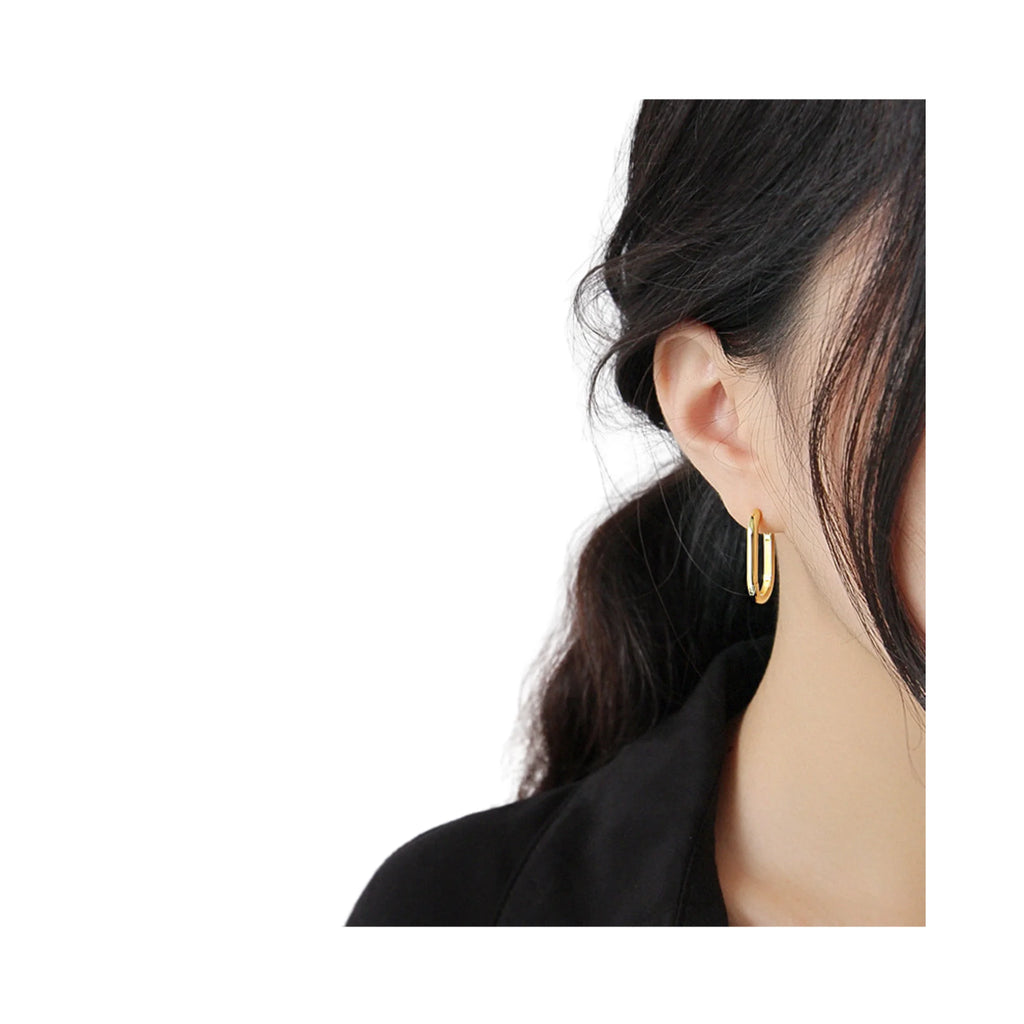 Goldfarbene ovale Ohrringe getragen am linken Ohr – dezent und flächig.