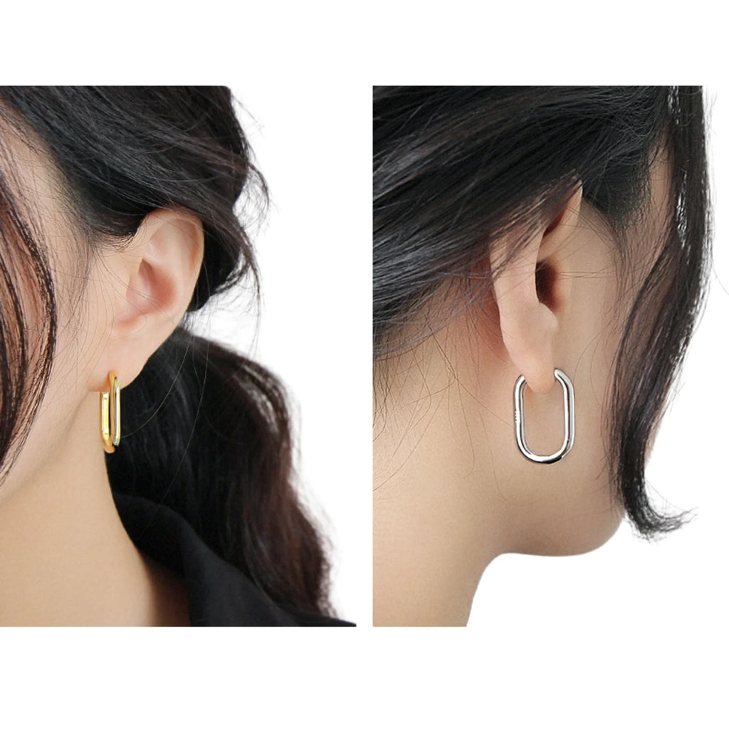Zwei ovale Ohrringe in Gold und Silber, getragen am Ohr – schlicht und glänzend.