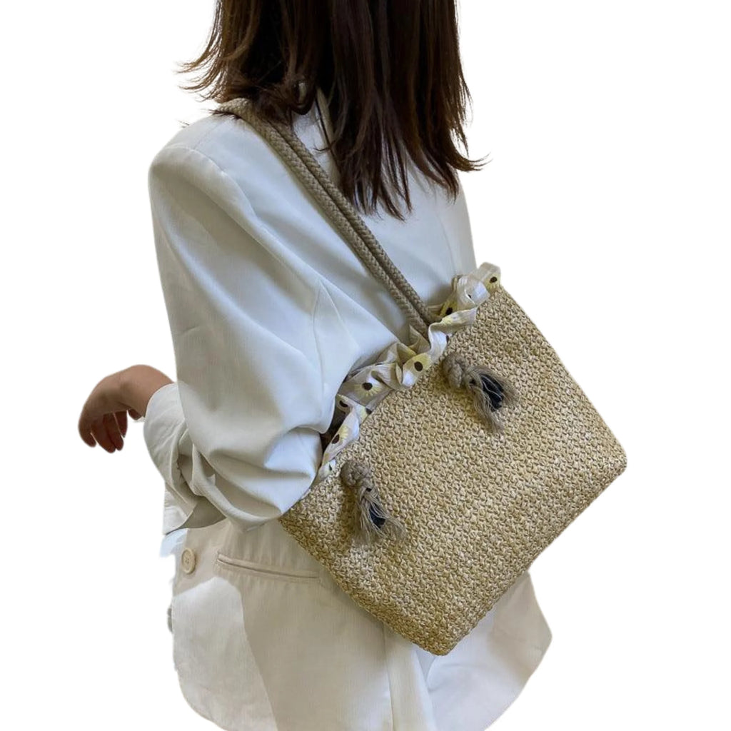 Frau trägt eine natürliche Raffia-Tasche mit Kordelverschluss über dem Rücken – ruhiger Sommerlook