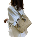 Frau trägt eine natürliche Raffia-Tasche mit Kordelverschluss über dem Rücken – ruhiger Sommerlook