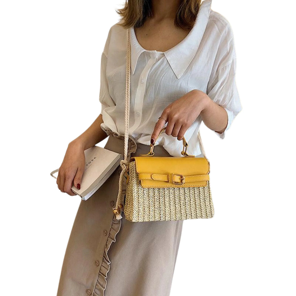 Kompakte Box-Tasche aus Rattan mit gelbem Lederdeckel und Schulterriemen – über weißer Bluse getragen