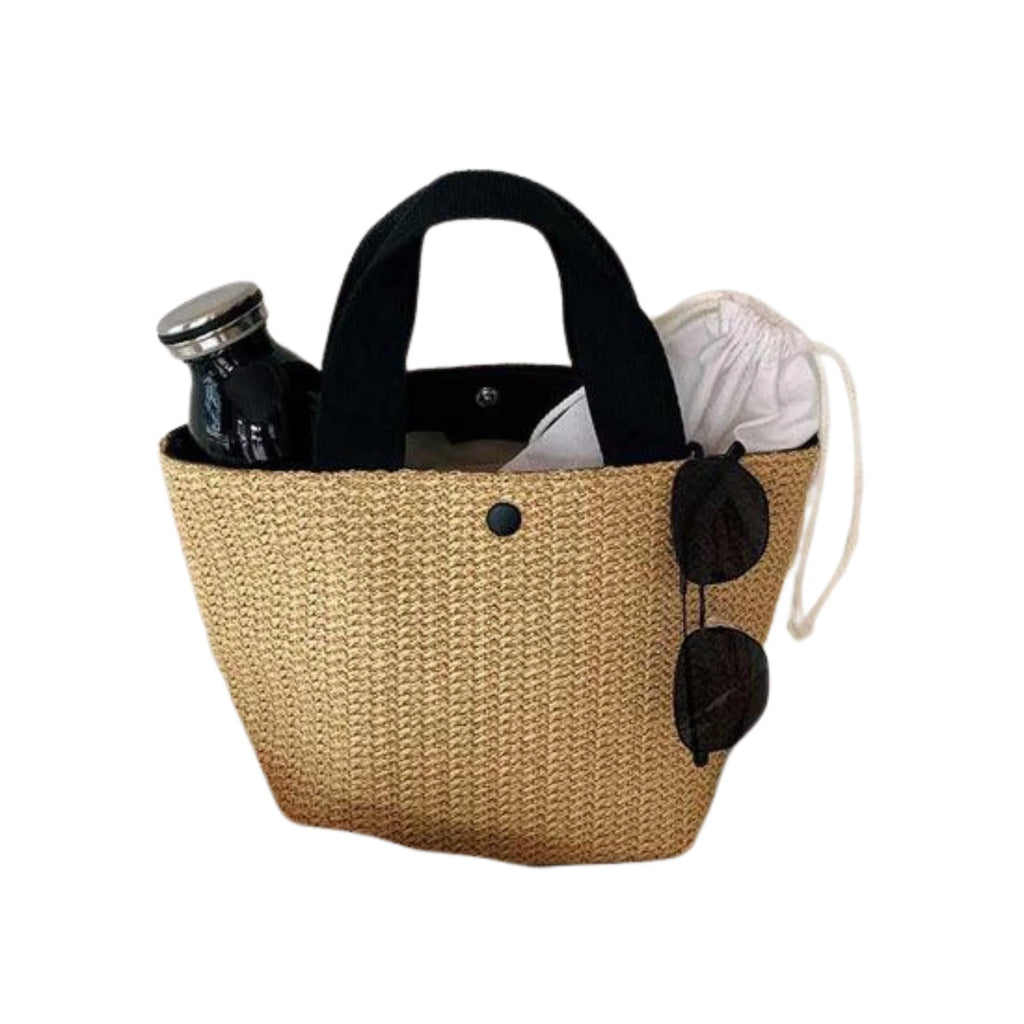 Kompakte Rattantasche mit schwarzem Griff und klarer Struktur – Inhalt sichtbar, mit Brille