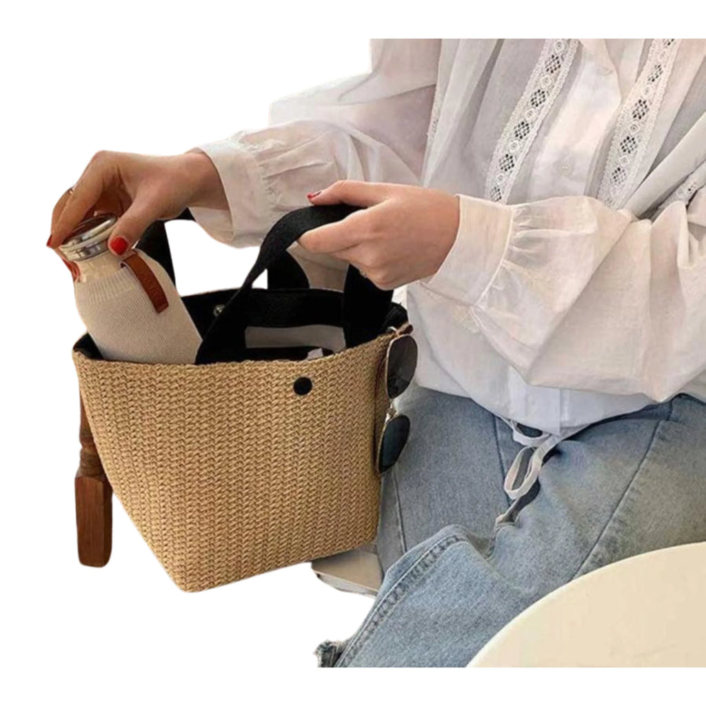 Shadow Black Version der Mini-Bucket-Bag – offen mit Flasche, getragen am Stuhl