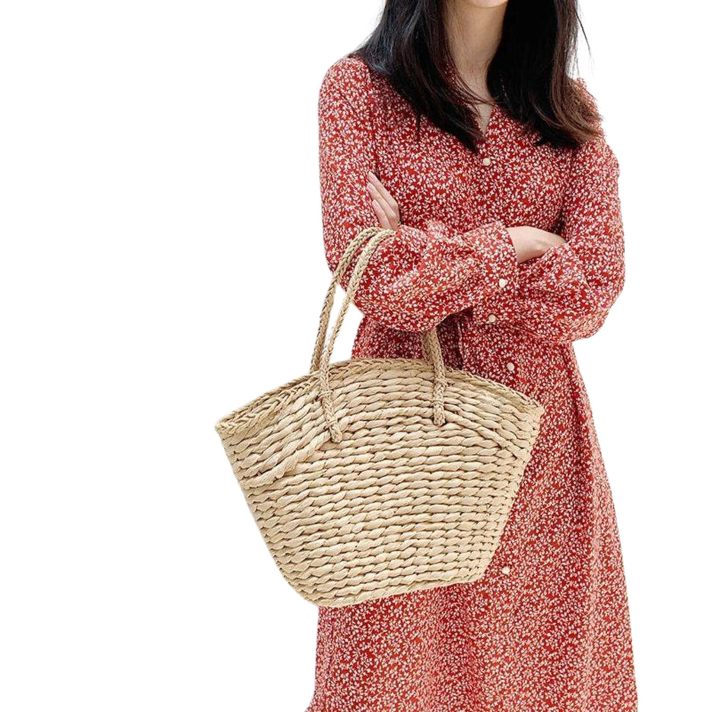 Geflochtene Alltagstasche aus Rattan, vorne getragen über rotem Kleid