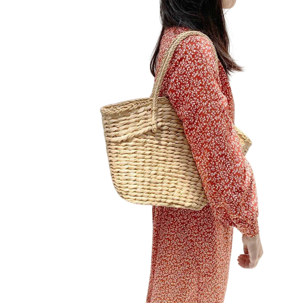 Frau mit Trapez-Shopper aus Rattan über der Schulter getragen – ruhiger Sommerlook