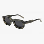 Rechteckige Sonnenbrille mit transparent grauem Rahmen und dunklen Gläsern.