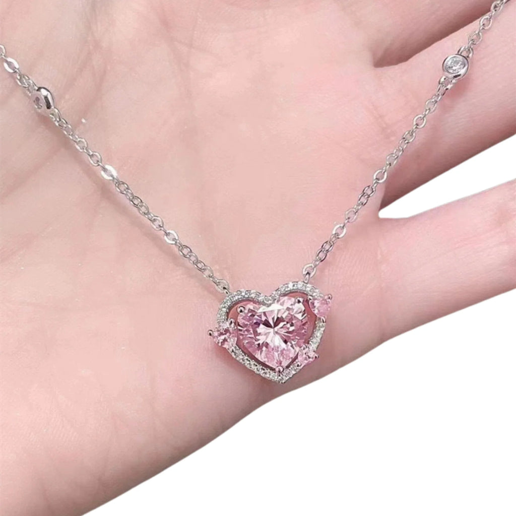 Herzanhänger mit rosa Zirkonia auf der Hand – klar eingefasst in silberfarbener Struktur