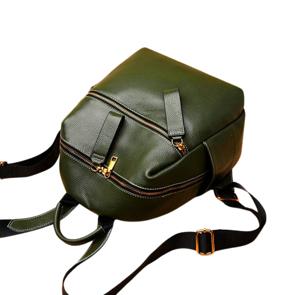 Rucksack in Deep Forest liegend gezeigt – zeigt weiche Struktur, goldene Zipper und ergonomische Gurte.