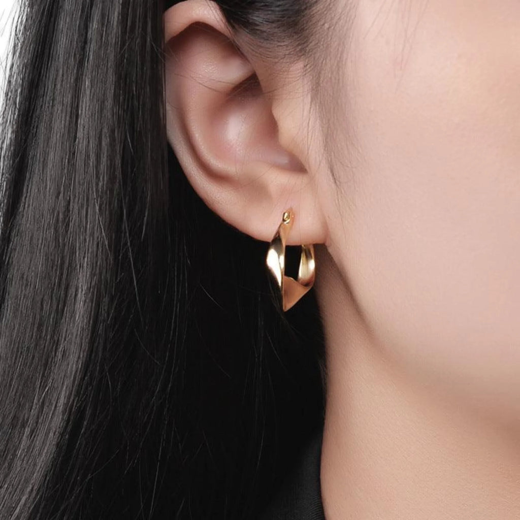 Goldene Creole mit verdrehter Fläche, getragen am Ohr