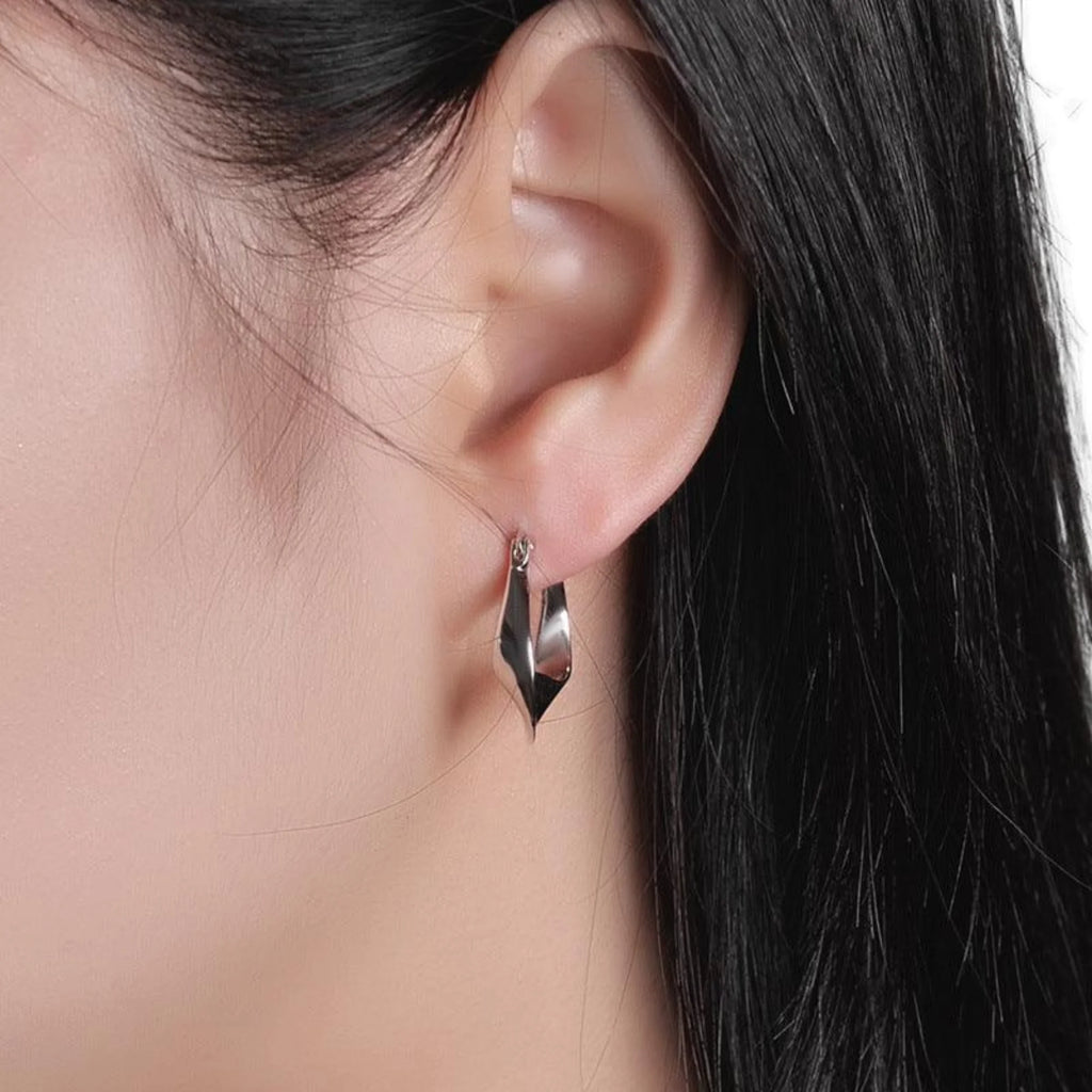 Silberne Creole mit glatter Drehung, am Ohr getragen